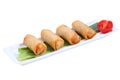 Four Chinese spring rolls on a white long, narrow plate. Royalty Free Stock Photo