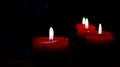 Four Christmas candles on the black background with blue bokeh.