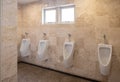 Four clean white urinals in public toilet
