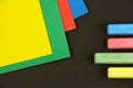 Four colored children crayons and papers on black background, top view, green chalk and paper select Royalty Free Stock Photo
