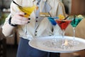 Four colored cocktails on a tray in the hands of the waiter. Yellow, blue, green, red. Waiter raises a yellow Royalty Free Stock Photo
