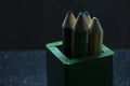 Four colored large pencils in a large green box on a dark background Royalty Free Stock Photo