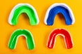 Four colored mouthguards on a yellow background, two adults and two children`s mouthguards, tooth protection, the concept of