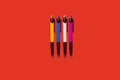 four colored pens lying on a red background Royalty Free Stock Photo