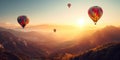 Four colorful hot air balloons floating over a mountainous landscape at sunrise with a small town in the distance Royalty Free Stock Photo