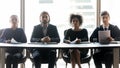 Four confident diverse hr managers sitting at table in row Royalty Free Stock Photo