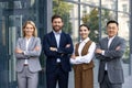 Four confident employees wearing business clothes and smiling widely to camera with arms folded on chest. Workers of Royalty Free Stock Photo