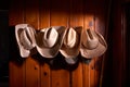 Four cowboy hats hung on wooden wall