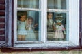 Four creepy dolls dressed in white and with traditional Romanian clothes, displayed in a window, while looking at the people Royalty Free Stock Photo