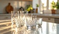 Four Crystal Glasses on White Kitchen Counter with Sunlight Reflections Royalty Free Stock Photo