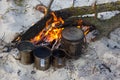 The four cups and kettle heats water on the fire. Camping beach, summer time, fireplace