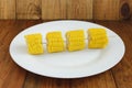 Four cut pieces of boiled corns on the plate on the wooden background Royalty Free Stock Photo