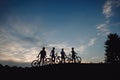 Four cyclist on hill at evening sky.