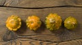 Four decorative pumpkins on burnt wooden background.