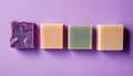 Four different colored soap bars on a purple background
