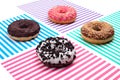 Four different donuts on striped multicolored stripes background top view