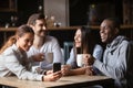 Four diverse friends having fun use gadget sitting in cafe Royalty Free Stock Photo
