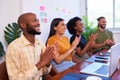Four diverse team members clapping hands at meeting presentation, tech team