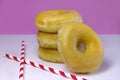 Four Donuts or Classic Donuts Stack with Two Red Stripe Straw on a White and Pink Background