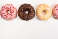 Four donuts in a row - white, pink and chocolate on a white background top view