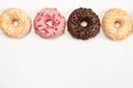 Four donuts in a row - white, pink and chocolate on a white background top view