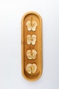 Four dried apple slices on oblong wooden plate on white background