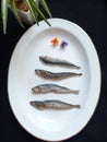 Four dried fish on a white plate