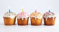Four Easter Kulich cakes with white icing adorned with colorful sprinkles with lit candle. Traditional Ukrainian Easter