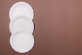 Four eco-friendly white paper plates lie on brown background with copy space. top view. close-up