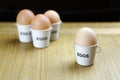 Four eggs in egg cups on a wooden table black background Royalty Free Stock Photo