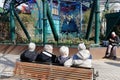 Four elderly people with gray hair are sitting and relaxing on a bench in the park. Royalty Free Stock Photo