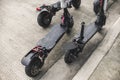 Four electric scooters parked by the side of a concrete road