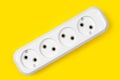 Four electrical sockets made of white plastic on a yellow background