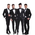 Four elegant young men in tuxedos standing together