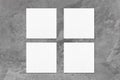 Four empty white square business card mockups on dark grey concrete background