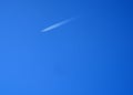 A four-engined jet with condensation trails behind it, against a blue sky. Royalty Free Stock Photo