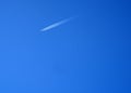 A four-engined jet with condensation trails behind it, against a blue sky.