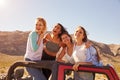 Four Female Friends On Road Trip Standing In Convertible Car