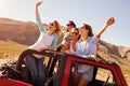 Four Female Friends On Road Trip Standing In Convertible Car