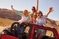 Four Female Friends On Road Trip Standing In Convertible Car