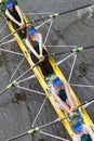 Four female rowers competing in regatta race in a yellow boat. shot from above