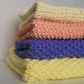 Four folded knitted blankets on a pile