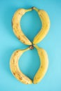 Four fresh bananas on a light blue background make the number 8. Flay lay minimal creative design.