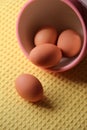 Four fresh brown eggs in stone bowl on yellow