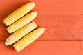 Four fresh sweet corn cobs on an orange table Royalty Free Stock Photo