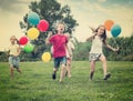 Four friendly glad kids running on green lawn