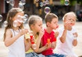 Four friendly kids blowing soap bubbles