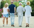 Four friendly mature people walking in the garden