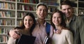 Friendly smiling schoolmates pose for camera in library