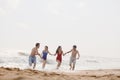 Four friends running out of the water on a sandy beach Royalty Free Stock Photo